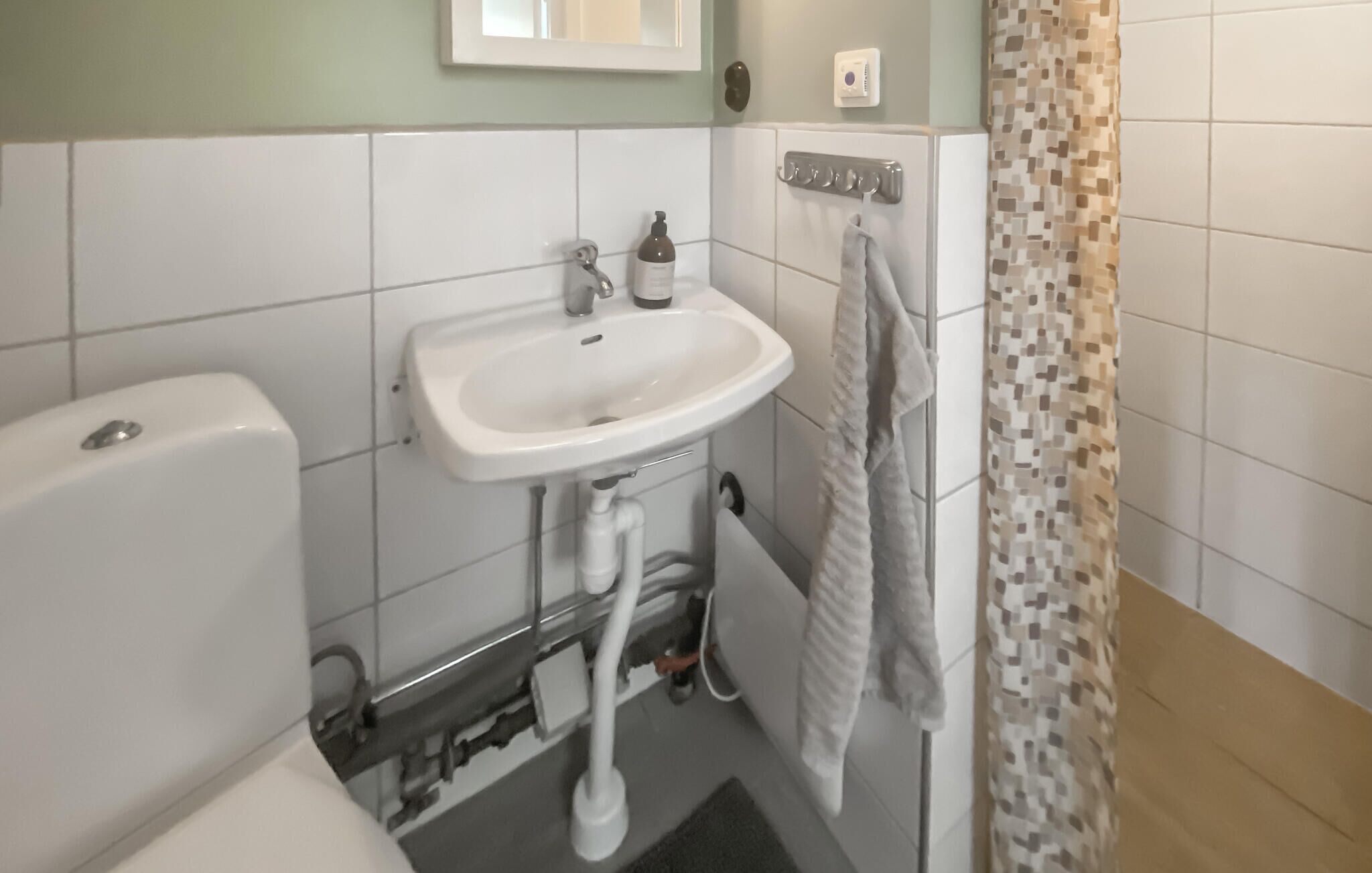 Et badeværelse med en hvid vask, toilet og bruseforhæng.