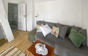 En stue med en grå sofa, et træbord og et tæppe med et mønster.