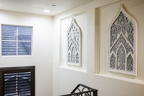 A room with a window, a decorative wall piece, and a black railing. - Luxury 7BR Getaway/10 Beds/Near Victoria Gardens (Rancho Cucamonga)