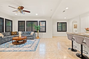 A spacious living area with a gray sofa, a wooden coffee table, and a blue patterned rug.