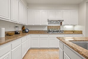 A kitchen with white cabinetry, granite countertops, a stainless steel stove, and a granite backsplash. - Luxury 7BR Getaway/10 Beds/Near Victoria Gardens (Rancho Cucamonga)