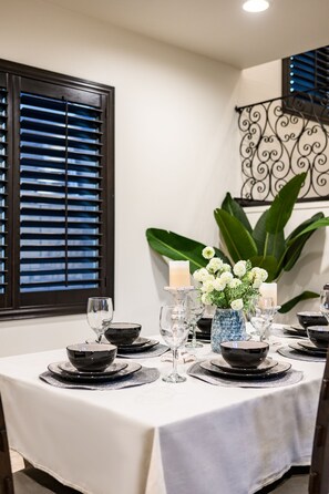 A dining table set with black bowls, glasses, and a vase with white flowers. - Luxury 7BR Getaway/10 Beds/Near Victoria Gardens (Rancho Cucamonga)
