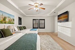 A bedroom with a bed, a ceiling fan, two windows with blinds, a painting on the wall, and a TV on the wall. - Luxury 7BR Getaway/10 Beds/Near Victoria Gardens (Rancho Cucamonga)