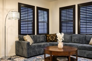 A living room with a grey sofa, a round wooden coffee table, and a floor lamp. - Luxury 7BR Getaway/10 Beds/Near Victoria Gardens (Rancho Cucamonga)
