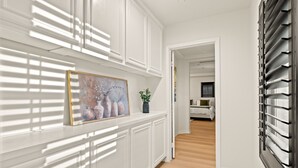A hallway with white paneling, a painting of vases, and a potted plant. - Luxury 7BR Getaway/10 Beds/Near Victoria Gardens (Rancho Cucamonga)
