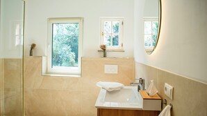 Ein modernes Badezimmer mit Duschkabine aus Glas, einem großzügigen Waschbecken und einem Fenster für natürliches Licht.