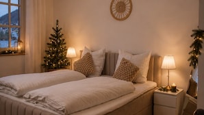 Ein Schlafzimmer mit einem Doppelbett, zwei Nachttischen, einer kleinen Weihnachtstanne und einer Wanddekoration.