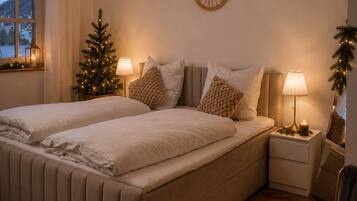 Un dormitorio con una cama doble, dos mesitas de noche, un pequeño árbol de Navidad y una decoración en la pared.