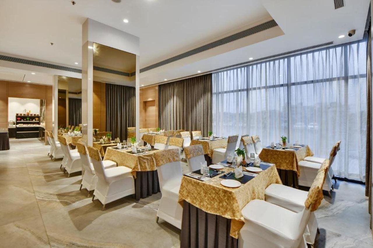 A hotel dining area with tables set for service, large windows, and a view of the city.