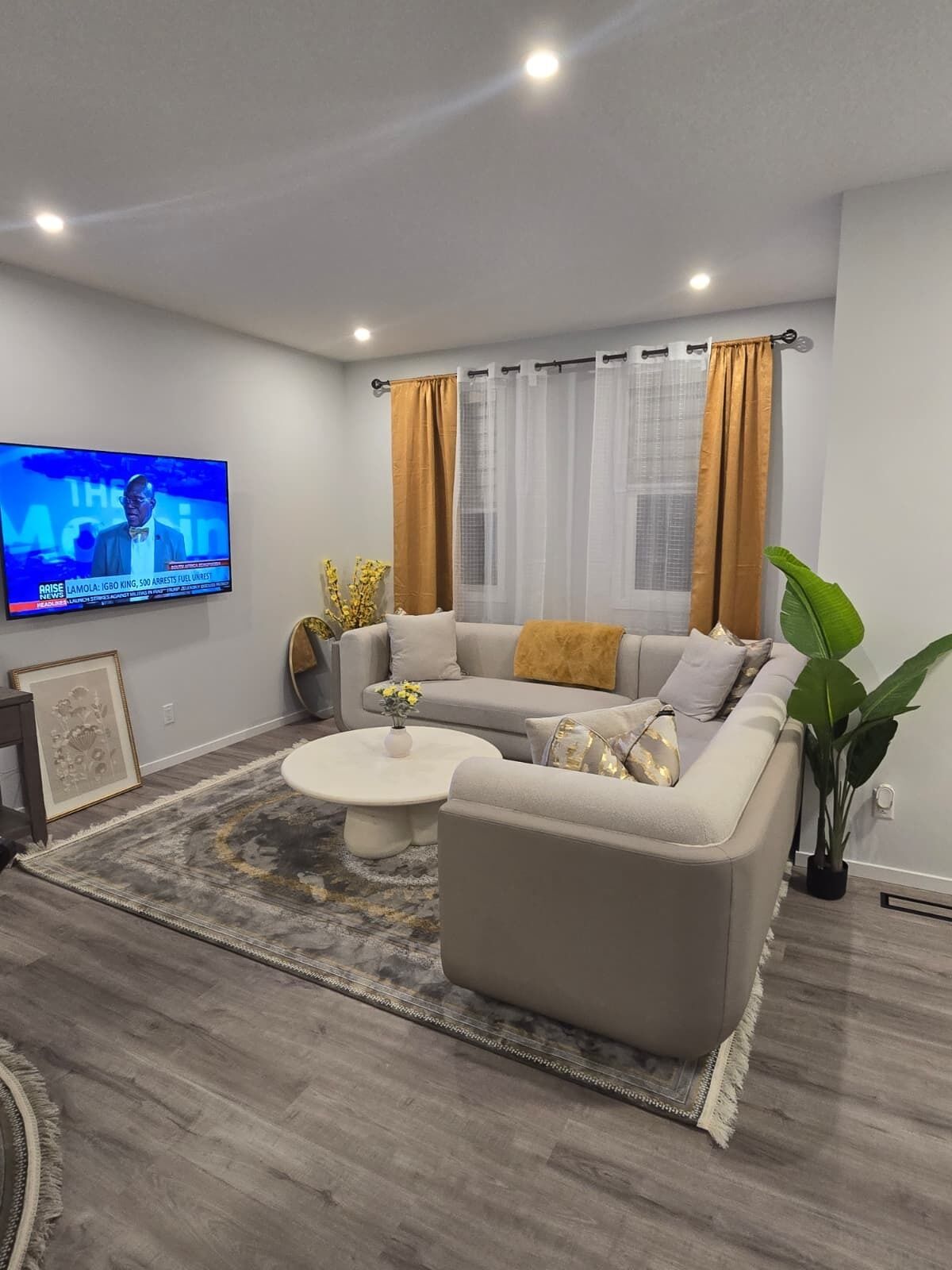 Un salon moderne avec un canapé gris, une table basse et un téléviseur fixé au mur.
