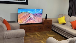 A living room with two patterned sofas, a flat-screen TV, a wooden cabinet, and a framed artwork on the wall. - Apartment in the Amauta 121 Housing Complex (Cusco)