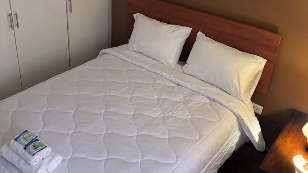 A hotel room with a bed, a wardrobe, and a nightstand. - Apartment in the Amauta 121 Housing Complex (Cusco)