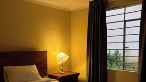 A hotel room with a bed, a nightstand, a lamp, and a window with curtains. - Apartment in the Amauta 121 Housing Complex (Cusco)