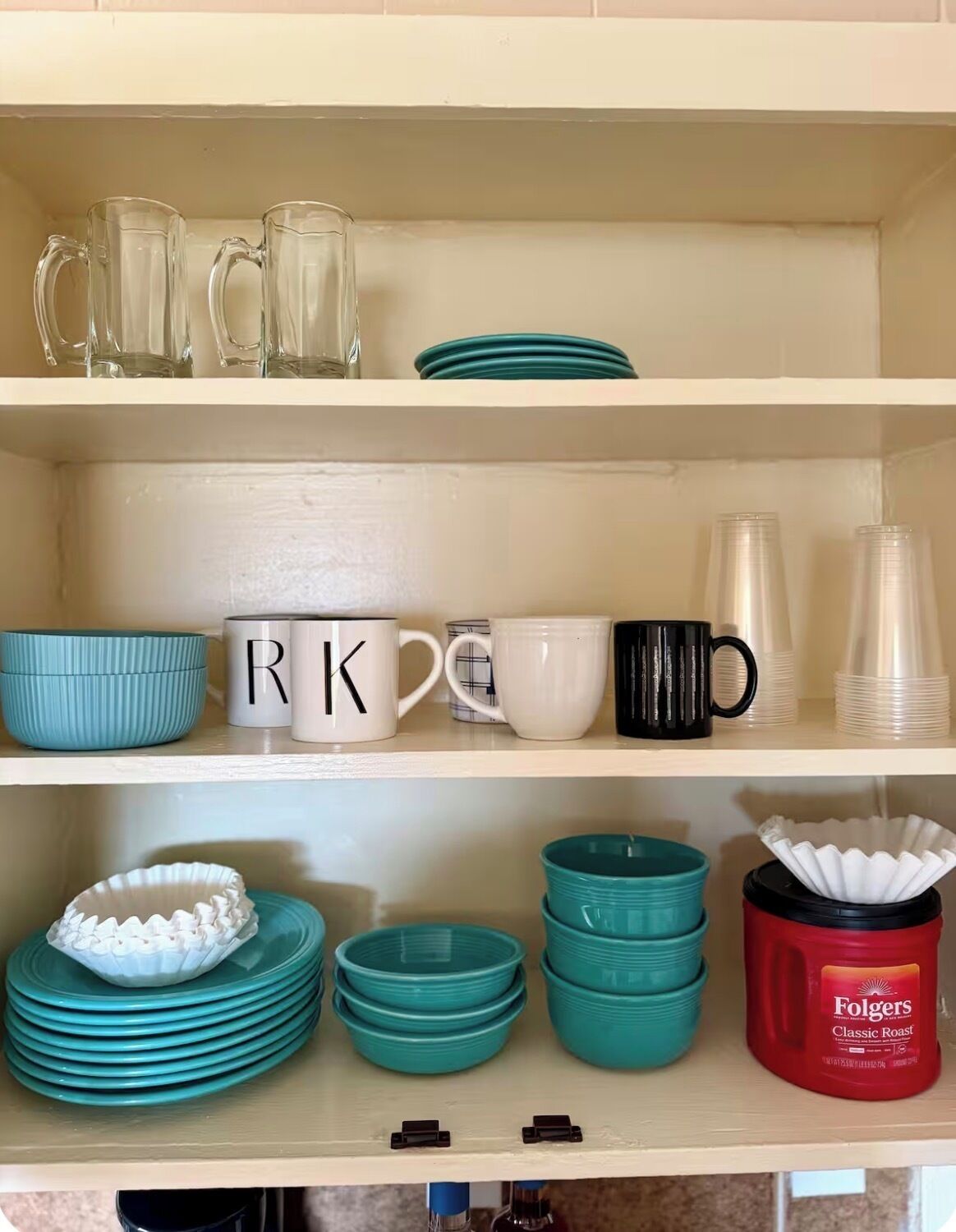 Una estantería de cocina con varias tazas, platos y una cafetera.