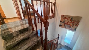 A staircase with wooden balusters and a marble floor.