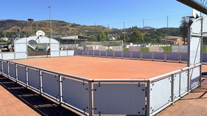 An outdoor sports court with a basketball hoop, surrounded by a fence, and a view of a hilly landscape in the background. - House with a View of Vineyards (Pet-Friendly) (Villamartín de Valdeorras)