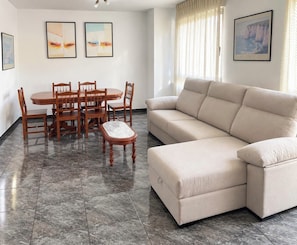 A living room with a beige sofa, a dining table with chairs, and artwork on the walls. - House with a View of Vineyards (Pet-Friendly) (Villamartín de Valdeorras)