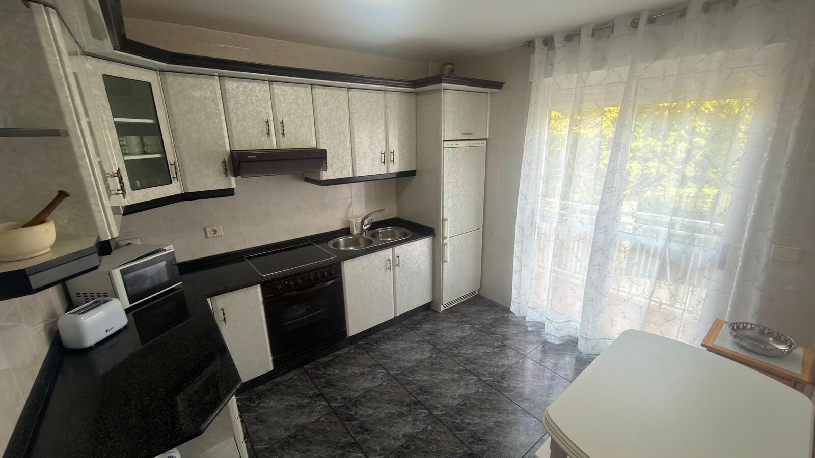 A compact kitchen with a stove, sink, and cabinets.