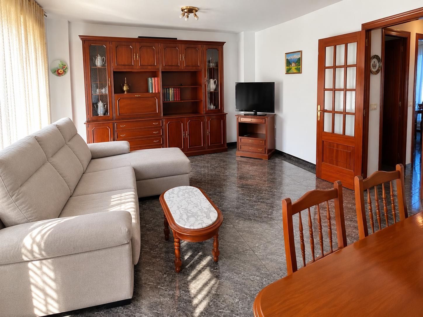 A living room with a sofa, a coffee table, a TV stand, and a wooden cabinet.