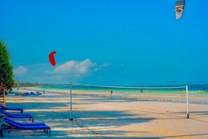 Una cancha de voleibol de playa con red, sillas de descanso y cielo despejado.