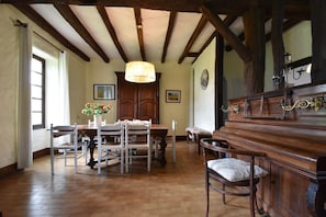 A dining room with a wooden table and chairs, a chandelier, and a piano. - Riverside Villa in Liglet with Swimming Pool (Liglet)