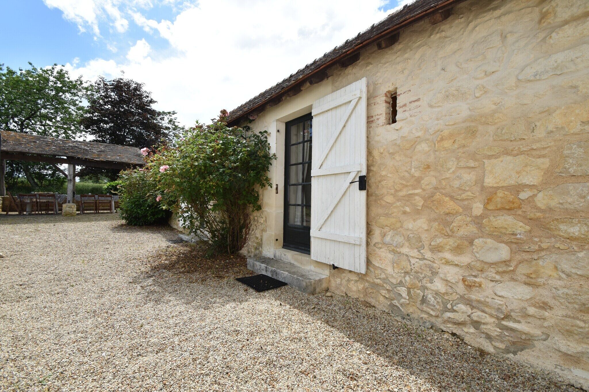 A stone building with a large white door and a gravel driveway.