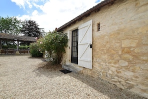 A stone building with a large white door and a gravel driveway. - Riverside Villa in Liglet with Swimming Pool (Liglet)