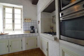 A kitchen with white cabinets, a stove, an oven, and a window.