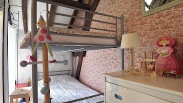 Un lit superposé avec une échelle, une petite table avec une lampe et une commode avec un miroir.