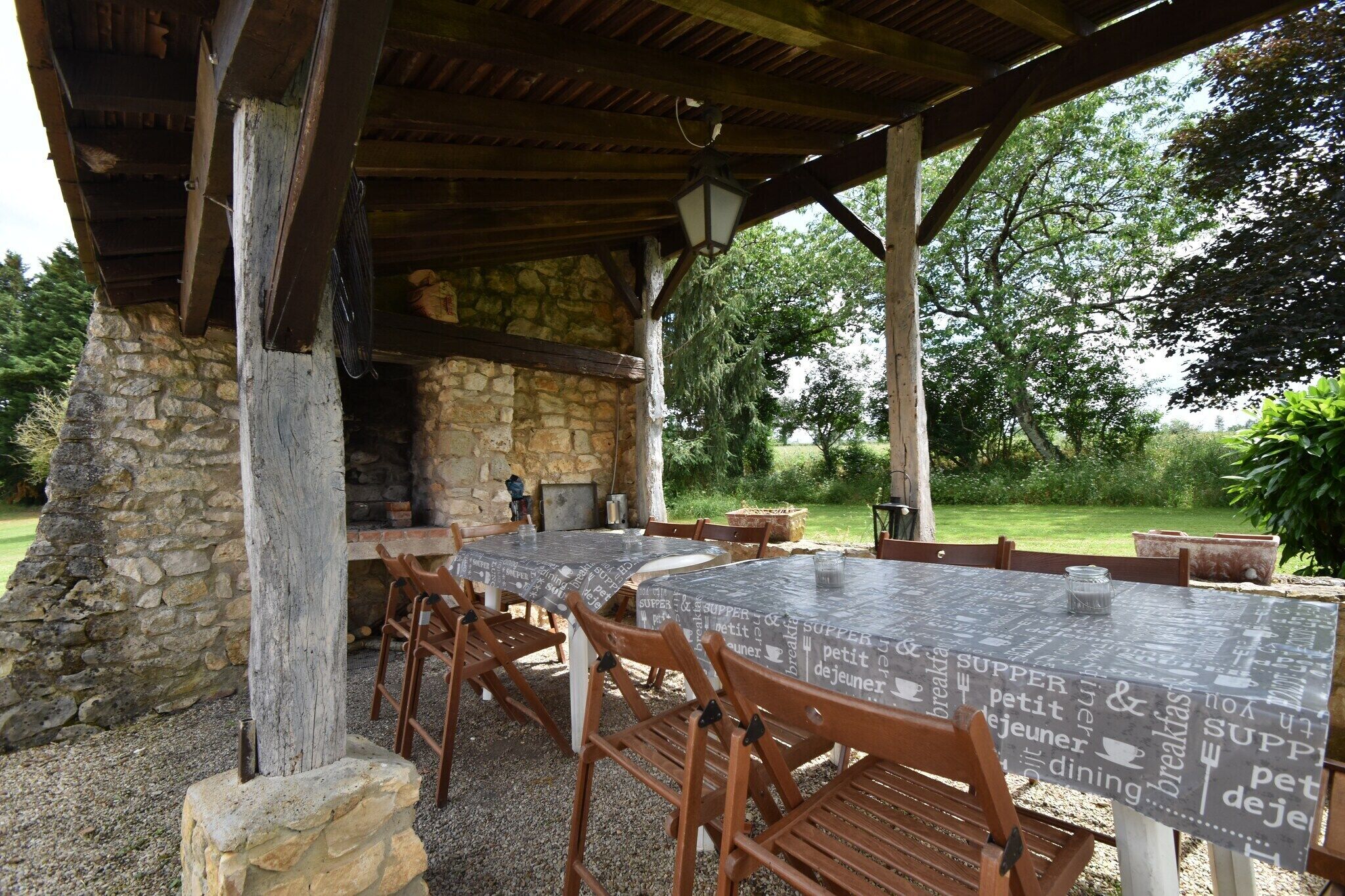 An outdoor dining area with stone walls, wooden tables, and chairs.