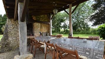 An outdoor dining area with stone walls, wooden tables, and chairs.