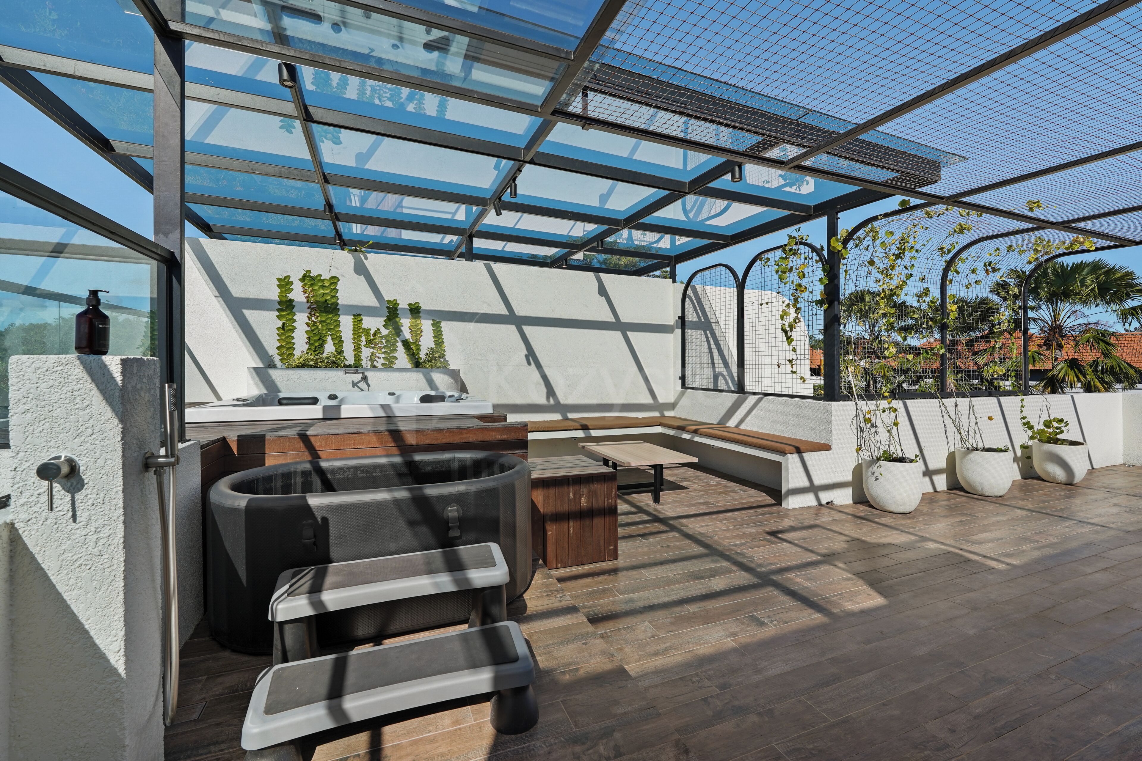 A rooftop terrace with a glass enclosure, outdoor seating, and potted plants.
