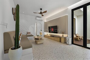 Una sala de estar moderna con un sofá, una mesa de centro, un televisor y un cactus.