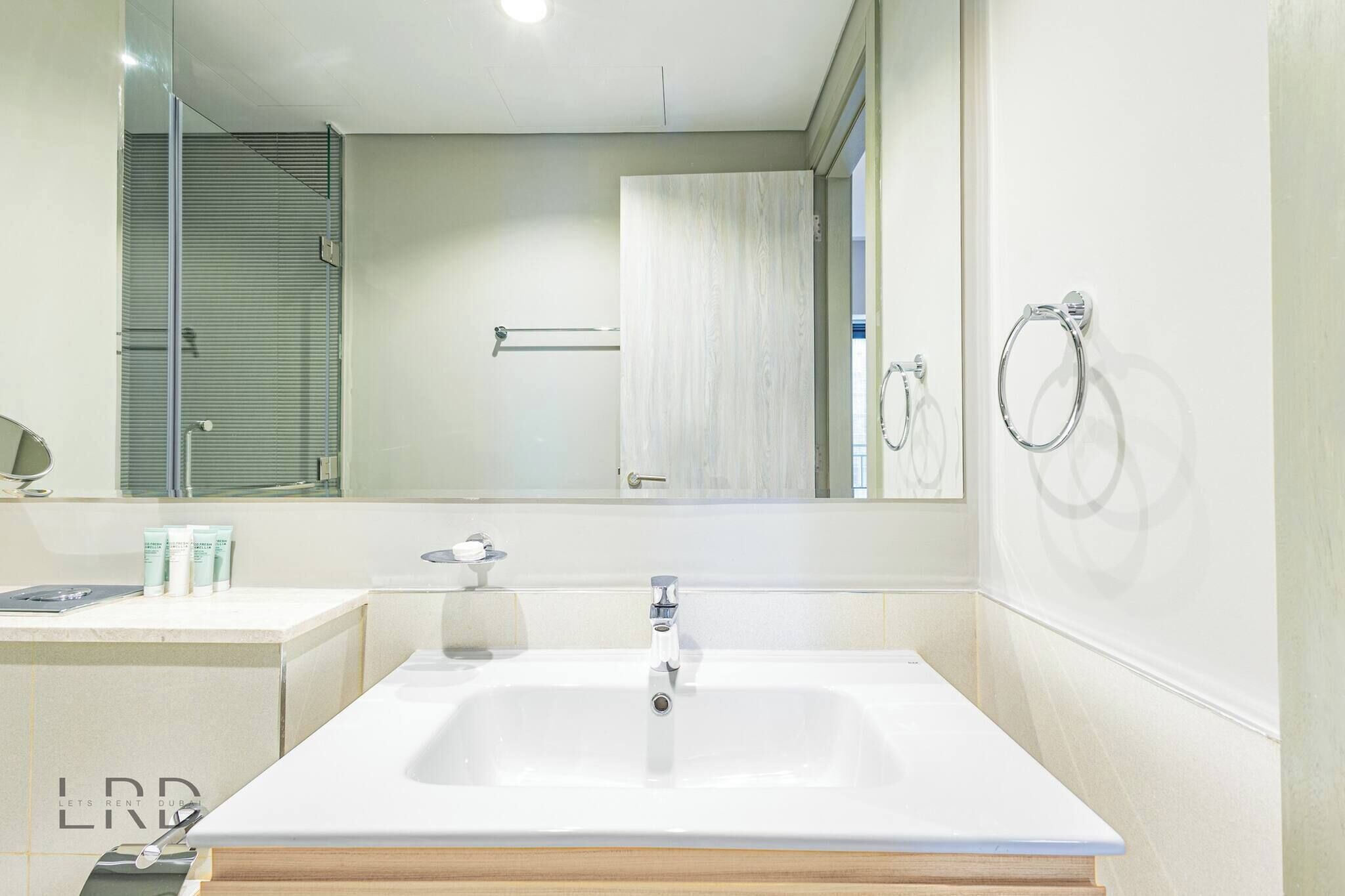 Une salle de bain moderne avec un grand lavabo rectangulaire, un miroir et un porte-serviettes.