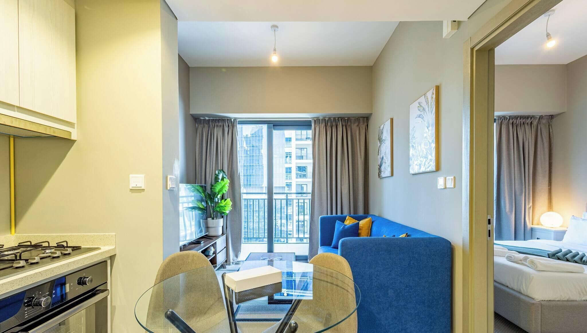 A compact living space with a kitchenette, a dining area, a sofa, and a bed.