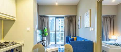 A compact living space with a kitchenette, a dining area, a sofa, and a bed.