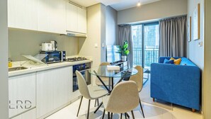 Et moderne køkken med spiseplads, en blå sofa og en balkon med gardiner.