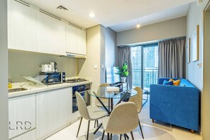 Eine moderne Küche mit Essbereich, einem blauen Sofa und einem Balkon mit Vorhängen.