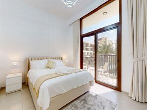 A bedroom with a bed, bedside tables, a window with curtains, and a view of the outside. - Modern 2BR | Fully Furnished | Great Amenities (Dubai)