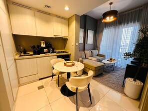 A modern kitchen with a dining area, a sofa, and a coffee table. - Fully Furnished 1BR | Near Metro Station | (Dubai)