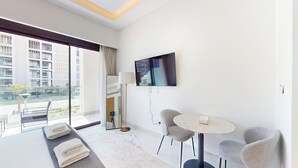 Habitación de hotel moderna con balcón, televisión de pantalla plana, una mesa redonda y un sofá.