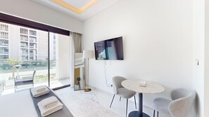 Ein modernes Hotelzimmer mit Balkon, Flachbildfernseher, rundem Tisch und einer Couch.
