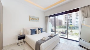 A modern hotel room with a large bed, a nightstand, a flat-screen TV, and a balcony with a view of the city. - Cozy Studio in Meydan | Premium Amenities (Dubai)