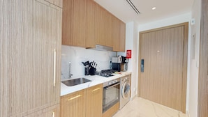Una cocina moderna con armarios de madera, un lavamanos de acero inoxidable, una estufa a gas, un horno empotrado y una lavadora.