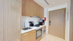 Eine moderne Küche mit Holzausbau, einer Edelstahlspüle, einem Gasherd, einem Backofen und einer Waschmaschine.