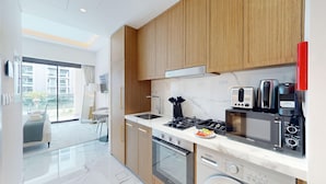 Una cocina moderna con armarios de madera, estufa a gas, microondas y tostadora.