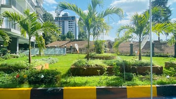 Un patio de hotel con piscina, abundante vegetación y una mezcla de edificios modernos y tradicionales al fondo.