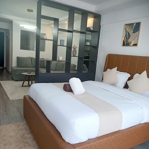 Et moderne hotelværelse med en stor seng, en sofa, et lille bord og et spejl.