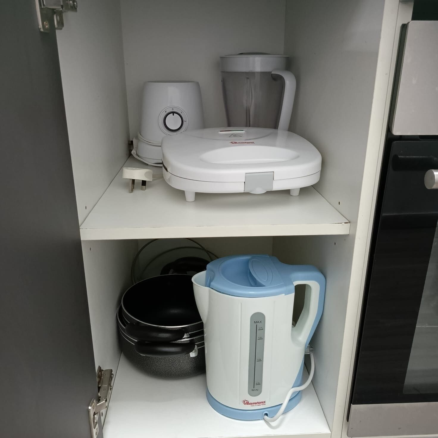 A kitchen with a coffee maker, a kettle, and a frying pan on the counter.