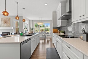 Uma cozinha moderna com ilha central, armários brancos e iluminação pendente.